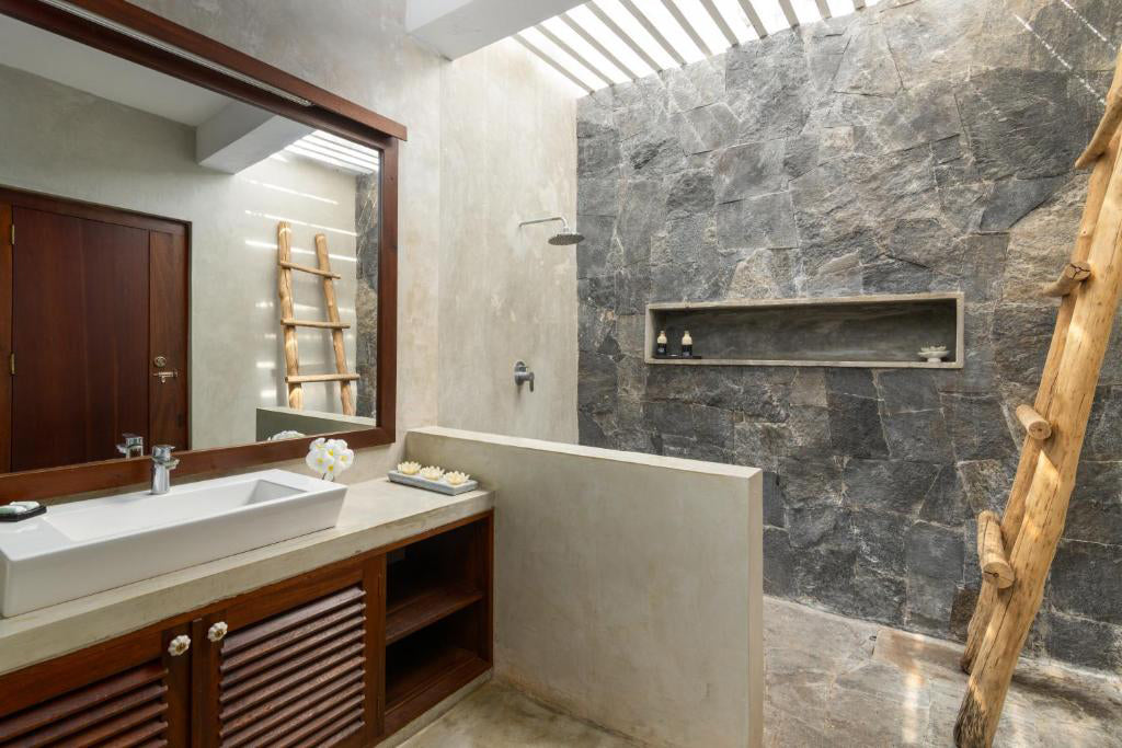 Interior view of a modern bathroom with a large walk-in shower, dark marble walls, and a wooden bench.