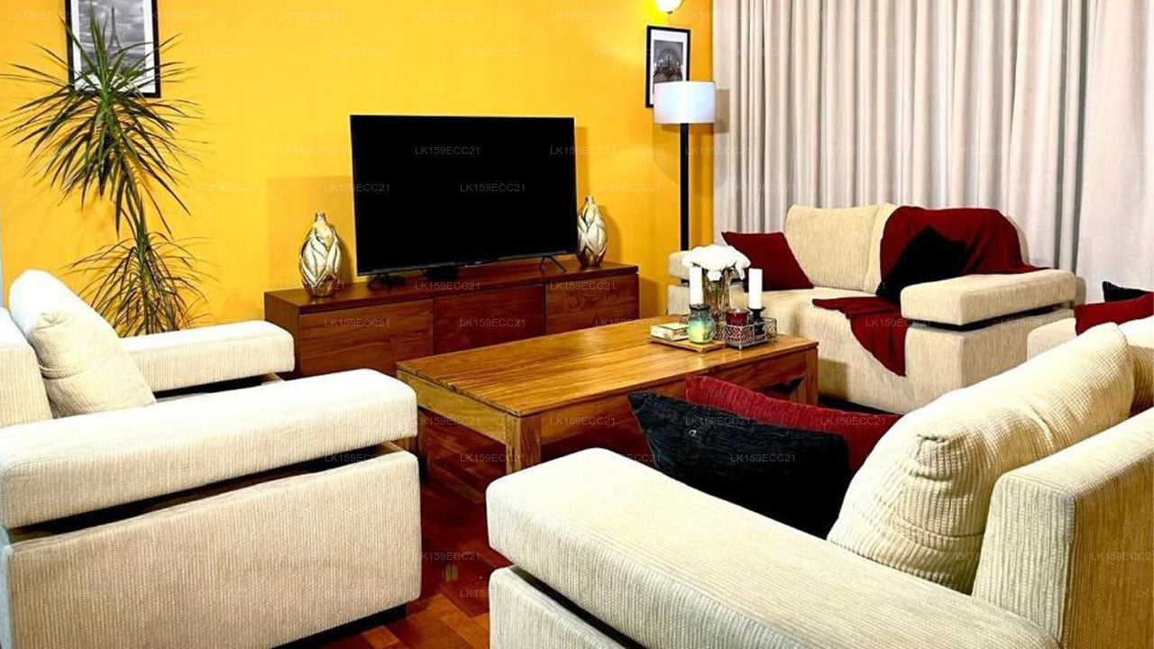 Living room with beige sofas, wooden coffee table, and a television on a yellow wall.