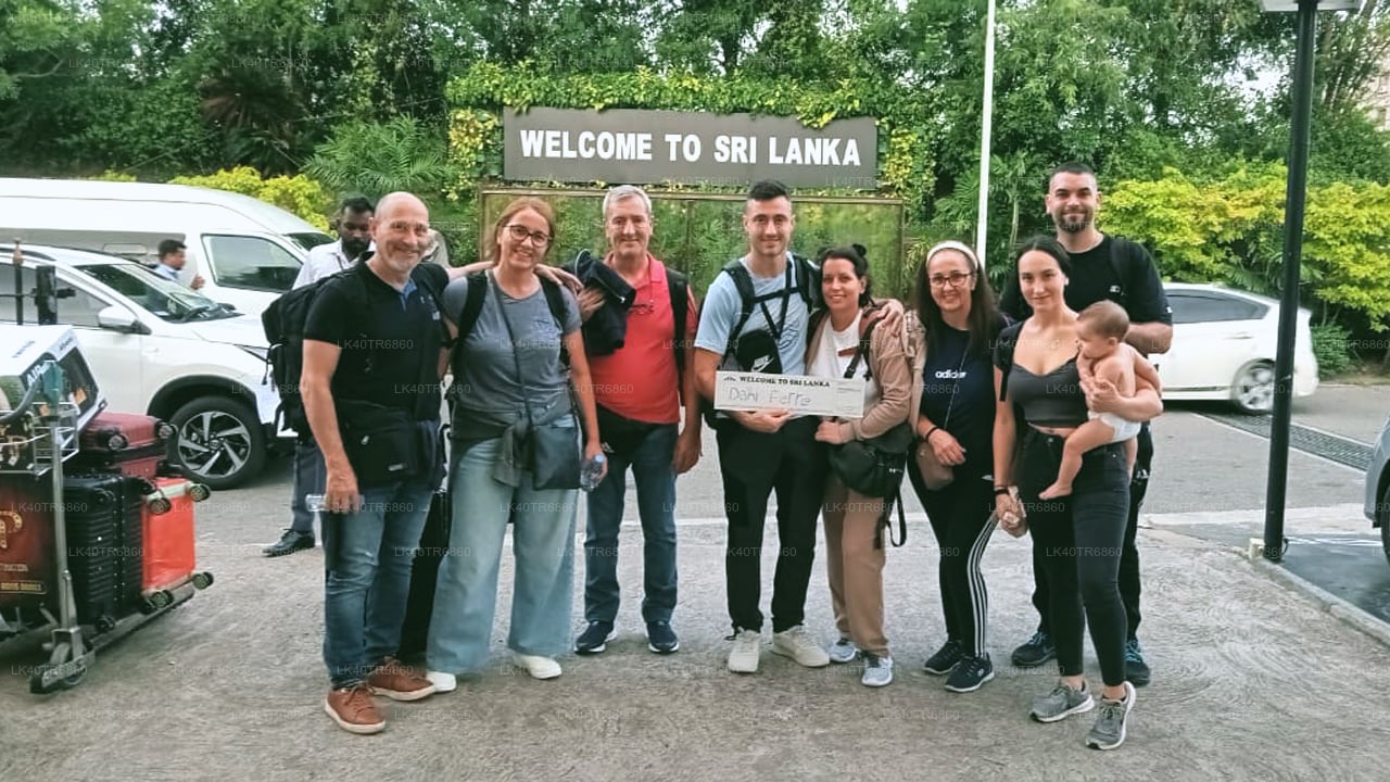 Group of people posing in front of a 'Welcome to Sri Lanka' sign at an airport.